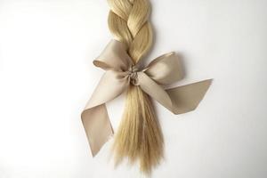 une tresse blonde avec un arc beige sur fond blanc photo