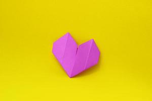 coeur d'origami en papier violet sur fond jaune au centre de la photo. fond minimaliste photo