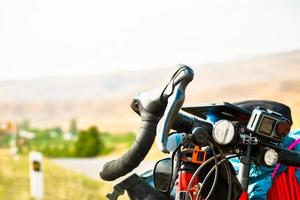 gros plan sur un support de vélo de randonnée sur une route de gravier pittoresque dans la campagne naturelle. machine de tourisme entièrement chargée avec fond d'espace de copie photo