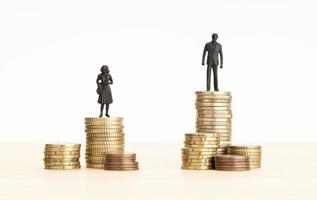 concept d'écart salarial entre les sexes. figurines homme et femme debout sur le tas de pièces photo