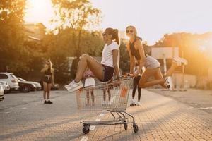 des amis montent sur des chariots, près du supermarché photo