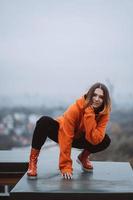 fille dans une veste orange pose sur le toit d'un immeuble du centre-ville photo