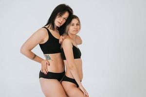 deux modèles différents portant des sous-vêtements se tiennent à côté de la caméra photo