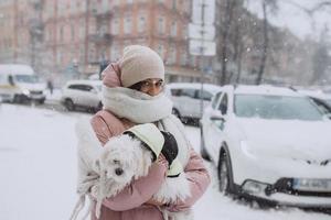 fille avec un chien dans les bras, la neige tombe photo