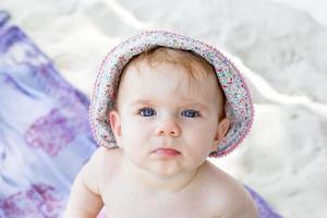 gros plan portrait jolie petite fille aux yeux bleus en panama d'été sur fond de sable blanc et de plaid. photo