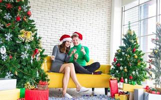 concept de joyeux noël et nouvel an. jeune amant caucasien avec des vêtements sur le thème de noël célébrer et échanger des cadeaux à la fête avec plaisir et bonheur photo