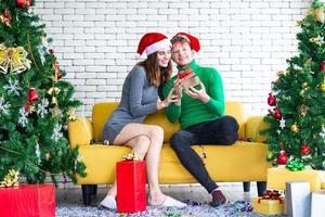 concept de joyeux noël et nouvel an. jeune amant caucasien avec des vêtements sur le thème de noël célébrer et échanger des cadeaux à la fête avec plaisir et bonheur photo