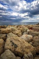 pierres colorées sur un rivage avec des nuages orageux à l'horizon. vue verticale photo