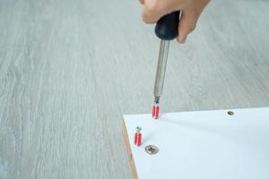 homme utilisant un tournevis pour assembler ou réparer des meubles à la maison. bricolage, rénovation, réparation et aménagement de concepts de maison ou d'appartement photo