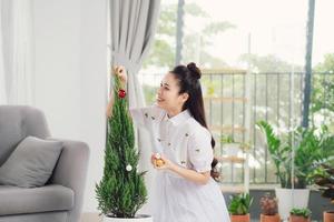 une femme décore un sapin de noël vivant dans un pot de fleurs. photo