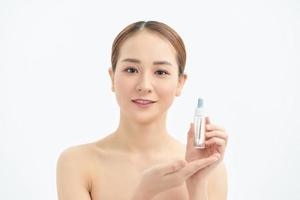 belle jeune femme asiatique montrant un produit de soin de la peau isolé sur fond blanc. photo