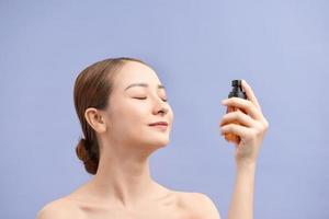 belle femme asiatique tenant une bouteille d'eau pulvérisée isolée sur fond blanc. photo