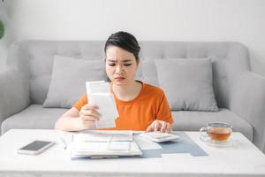 jeune femme asiatique stressée tenant tant de factures de dépenses dans sa main pas d'argent pour payer la dette photo