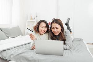 deux femmes heureuses faisant des achats en ligne avec carte de crédit et ordinateur portable à la maison