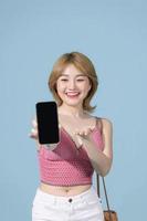 charmante adorable jeune belle femme asiatique portant un haut rose tenant un appareil moderne, montrant un smartphone à écran noir photo