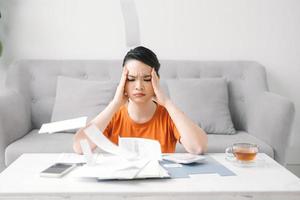 jeune femme asiatique stressée tenant tant de factures de dépenses dans sa main pas d'argent pour payer la dette photo