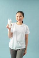 femme souriante tenant un verre de lait sur un fond bleu photo