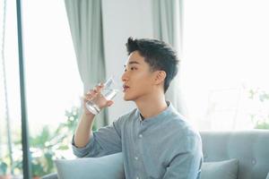 portrait d'un jeune homme buvant un verre d'eau photo