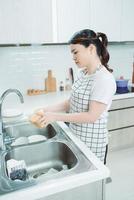 jeune femme a lavé la vaisselle dans une cuisine photo