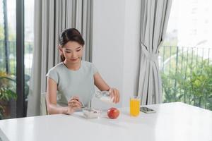 femme versant du lait sur une assiette avec de la mousseline de céréales à la cuisine photo
