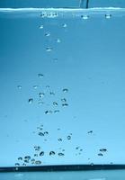 image de fond abstrait de bulles dans l'eau. eau propre avec des gouttelettes d'eau et des vagues. eau douce un verre avec fond bleu bulles. photo