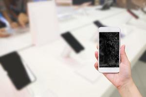 Tenir la main téléphone mobile avec écran en verre cassé avec abstract blur boutique électronique pour smartphone fix concept photo