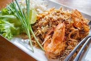 pad thaï, nouilles de riz sautées aux crevettes d'eau douce servies avec légumes, pousses et citron photo