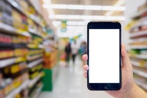 une femme tient un téléphone portable pendant qu'elle fait ses courses dans un supermarché photo