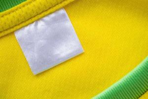 Étiquette de vêtements textiles blanc vierge sur la texture de jersey de tissu de vêtements de sport jaune photo