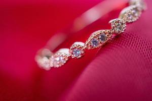 bijoux bague en or rose de luxe avec pierre précieuse saphir sur fond de texture de tissu rouge photo