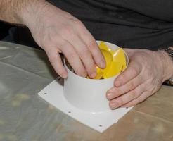 le processus d'assemblage du ventilateur d'extraction de la cuisine après le nettoyage du lavage. un homme travaille avec un tournevis dans les mains photo