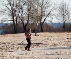 dnepr, ukraine - 21.02.2022 un homme d'âge moyen fait de la gymnastique sur la rive du fleuve. le concept d'un mode de vie sain et la lutte contre le poids des lignes. photo