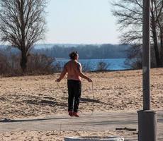 dnepr, ukraine - 21.02.2022 un homme d'âge moyen fait de la gymnastique sur la rive du fleuve. le concept d'un mode de vie sain et la lutte contre le poids des lignes. photo