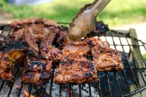 côtes levées cuisinant sur le gril, barbecue de bœuf et de porc en plein air photo