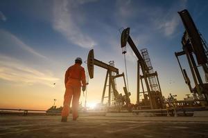 silhouette de travailleurs pétroliers travaillant dans une plate-forme pétrolière ou des champs pétrolifères et une station-service le soir avec un beau coucher de soleil. photo