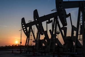 plate-forme pétrolière ou site de champ pétrolifère, le matin ou le soir, les pompes à huile fonctionnent, la pompe à huile et le magnifique coucher ou lever de soleil de l'unité de pompage. photo