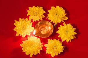 fête de la lumière indienne de diwali. lampe à huile diya et fleurs jaunes sur fond rouge. fête hindoue traditionnelle. photo