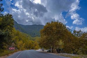 route à travers la forêt d'automne dans les montagnes. route de la forêt d'automne. autoroute dans la forêt d'automne. beau paysage de route de l'autoroute de la forêt d'automne photo