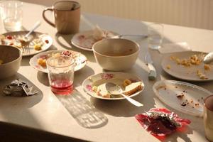 vider les assiettes sales avec des cuillères et des fourchettes sur la table après le repas. concept de fin de banquet. vaisselle non lavée photo