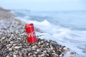 antalya, turquie - 18 mai 2021 la boîte de conserve rouge coca cola originale se trouve sur de petits cailloux ronds près du bord de mer. coca-cola sur la plage turque photo