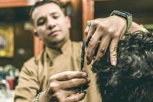 gros plan des mains d'un barbier coupant les cheveux d'un homme. photo