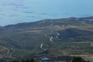 route de montagne sinueuse traversant la forêt sur fond de mer. vue d'en-haut. paysage photo