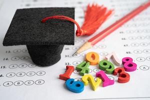 nombre mathématique coloré avec chapeau de graduation et crayon sur fond de feuille de réponses, étude de l'éducation apprentissage des mathématiques concept d'enseignement. photo