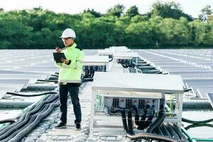 électricien masculin en casque de sécurité blanc debout sur une échelle et montage d'un panneau solaire photovoltaïque sous un beau ciel bleu. concept de sources d'énergie alternatives. photo