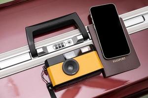 concept de voyage appareil photo vintage, smartphone et passeport sur fond de bagages rouge, avec espace de copie.