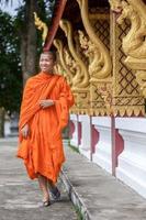 jeune moine bouddhiste marchant à côté du temple photo