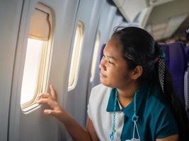 femme asiatique assise regardant par la fenêtre de l'avion photo