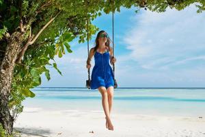 femme en robe bleue se balançant sur la plage