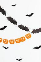 concept de truc ou de friandise. composition de vacances avec des décorations de guirlande d'halloween citrouilles et chauves-souris isolés sur fond blanc. préparation pour la fête d'halloween. automne tomber joyeux halloween photo