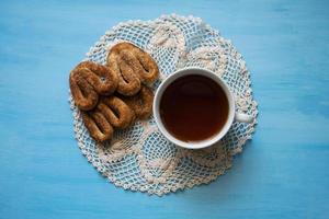 coquelicot avec des bretzels sur un tableau bleu avec une tasse de thé. une tasse de thé et des bretzels à la cannelle. photo